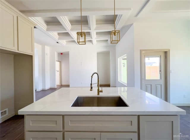 kitchen featuring coffered ceiling, light stone countertops, decorative light fixtures, beamed ceiling, and sink