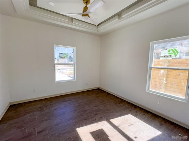 spare room featuring dark wood-type flooring, ceiling fan, and a tray ceiling