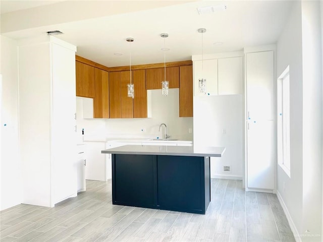 kitchen with light wood-type flooring, a kitchen island, light countertops, and a sink