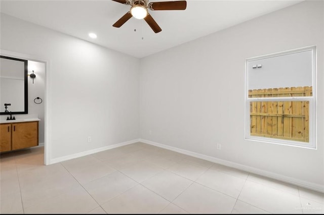 empty room featuring light tile patterned flooring, a sink, baseboards, and ceiling fan