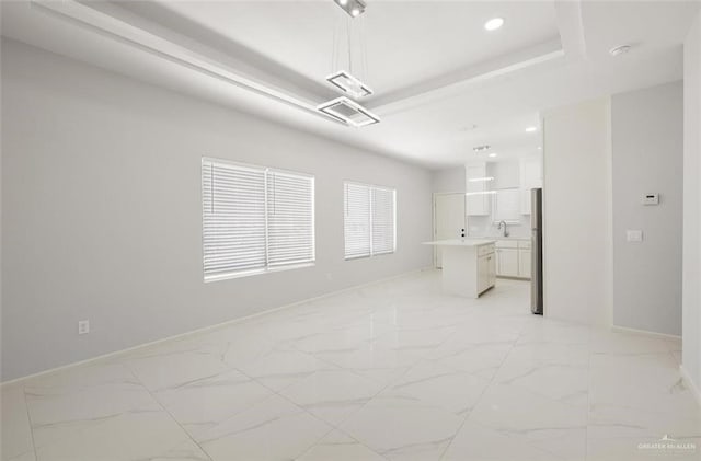 interior space featuring a raised ceiling, marble finish floor, a sink, and baseboards