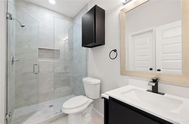 full bathroom with vanity, a shower stall, toilet, and baseboards