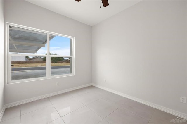 spare room featuring light tile patterned floors, ceiling fan, and baseboards