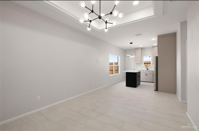 kitchen with a raised ceiling, light countertops, freestanding refrigerator, open floor plan, and a kitchen island