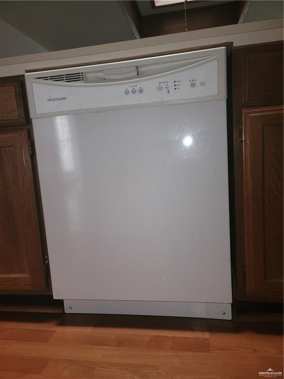 room details with white dishwasher, dark brown cabinets, and light wood-type flooring