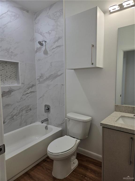 901 E Yuma Ave Unit 206, Mcallen, TX 78503 - bathroom with baseboards, wood finished floors, toilet, vanity, and shower / bathtub combination