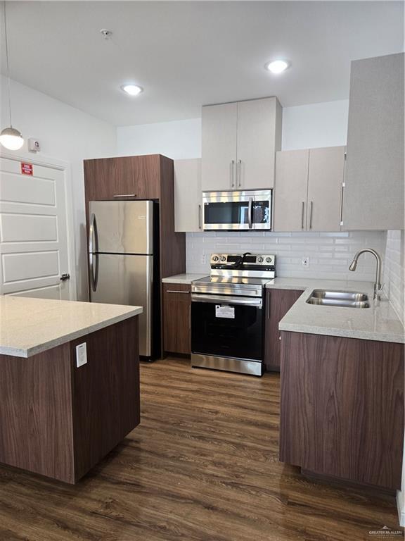 901 E Yuma Ave Unit 206, Mcallen, TX 78503 - kitchen with a sink, hanging light fixtures, dark wood-style floors, stainless steel appliances, and decorative backsplash