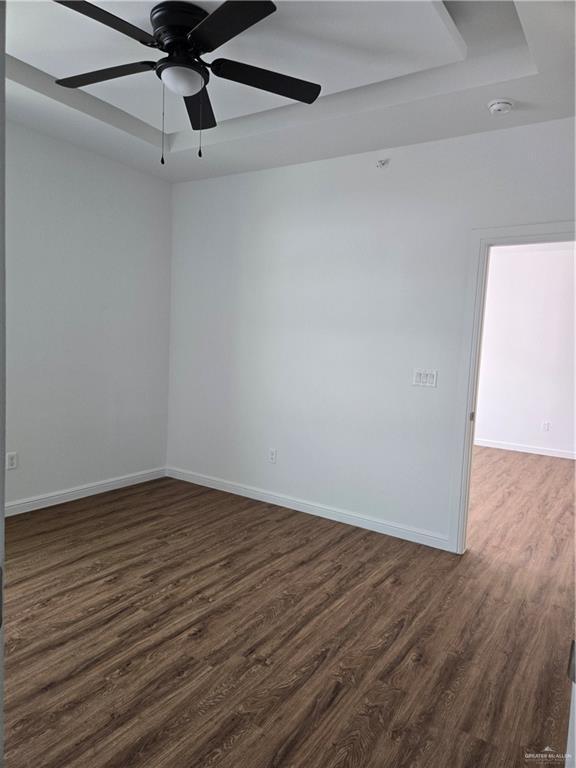 901 E Yuma Ave Unit 206, Mcallen, TX 78503 - unfurnished room with baseboards, a ceiling fan, dark wood-type flooring, and a raised ceiling