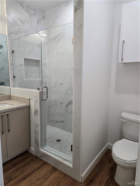 901 E Yuma Ave Unit 206, Mcallen, TX 78503 - full bathroom featuring baseboards, a marble finish shower, wood finished floors, toilet, and vanity