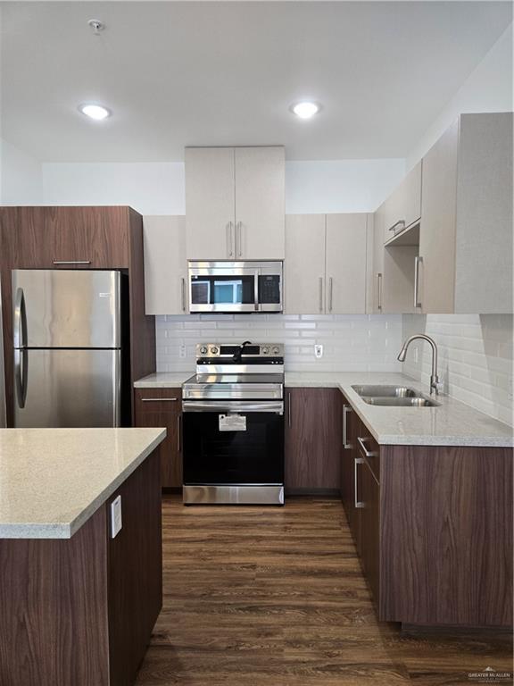 901 E Yuma Ave Unit 206, Mcallen, TX 78503 - kitchen featuring light countertops, a sink, dark wood finished floors, stainless steel appliances, and decorative backsplash