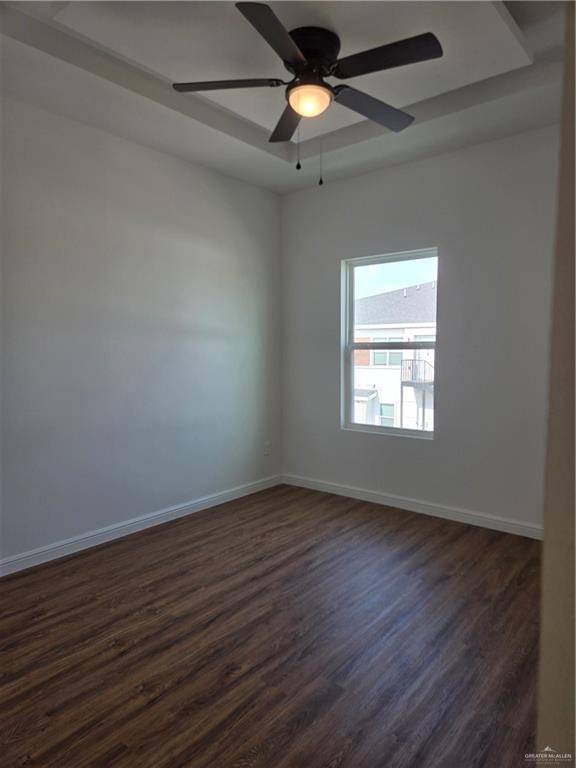901 E Yuma Ave Unit 206, Mcallen, TX 78503 - empty room featuring baseboards, dark wood-style flooring, ceiling fan, and a raised ceiling