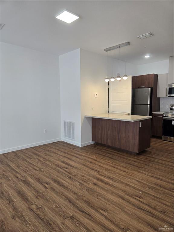 901 E Yuma Ave Unit 206, Mcallen, TX 78503 - kitchen featuring light countertops, a peninsula, dark wood-style floors, stainless steel appliances, and visible vents