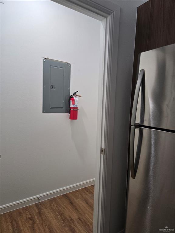 901 E Yuma Ave Unit 206, Mcallen, TX 78503 - room details with electric panel, baseboards, a fire extinguisher, freestanding refrigerator, and wood finished floors