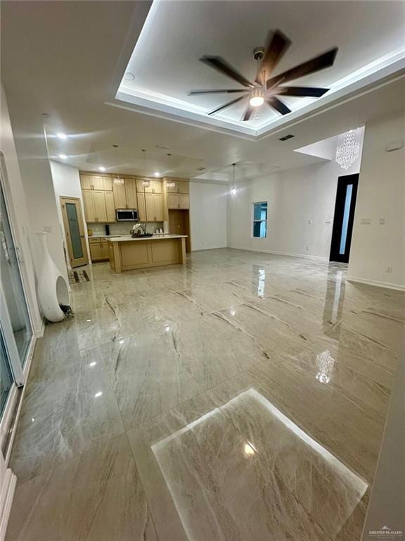 unfurnished living room with a raised ceiling and ceiling fan