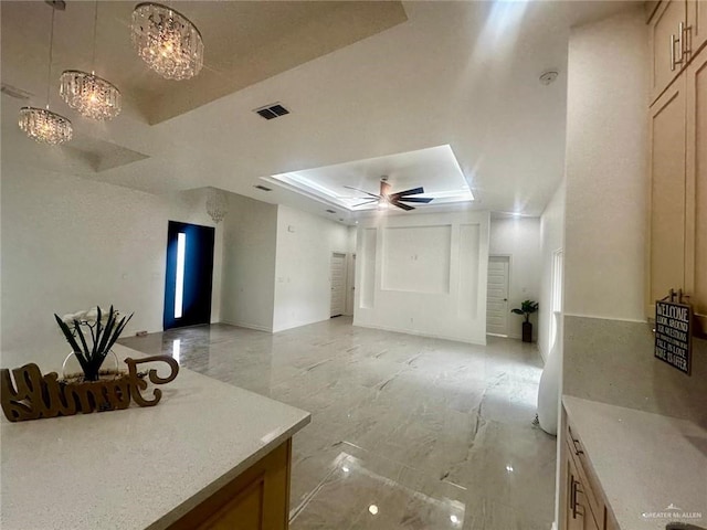 interior space featuring ceiling fan with notable chandelier and a raised ceiling