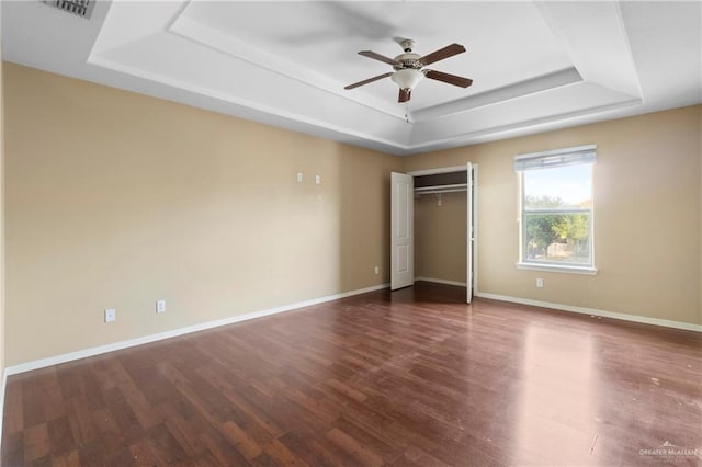 unfurnished bedroom with dark hardwood / wood-style floors, ceiling fan, a raised ceiling, and a closet