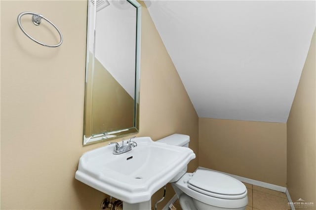 bathroom with tile patterned floors, toilet, lofted ceiling, and sink