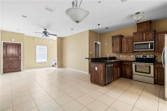 kitchen featuring pendant lighting, dark stone counters, sink, appliances with stainless steel finishes, and tasteful backsplash