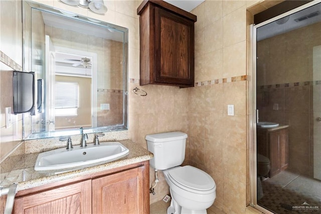 bathroom featuring vanity, tile walls, and toilet