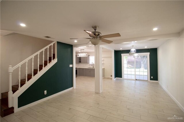 unfurnished living room featuring a sink, visible vents, recessed lighting, a ceiling fan, and stairs