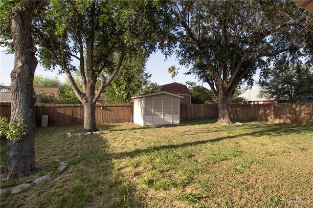 view of yard with a fenced backyard, an outbuilding, and a storage shed