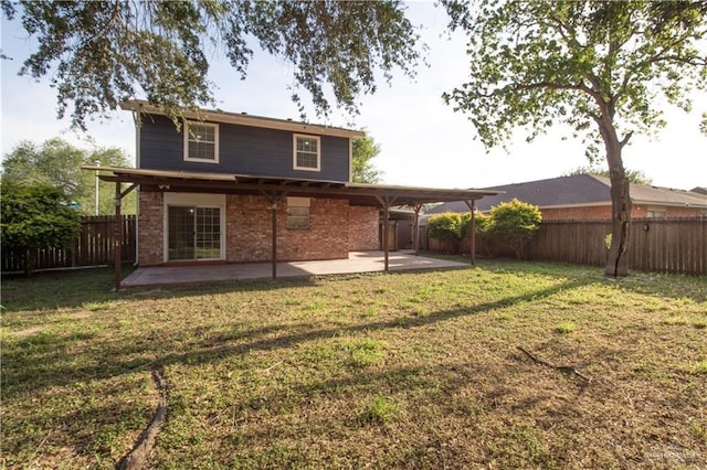 rear view of house featuring brick siding, a yard, a fenced backyard, and a patio