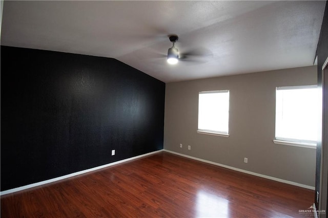 unfurnished room with lofted ceiling, wood finished floors, a ceiling fan, and baseboards
