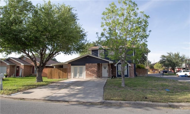 traditional-style home with driveway, french doors, fence, a front yard, and brick siding