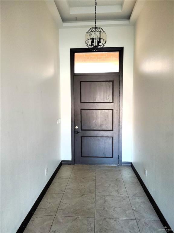 doorway to outside with an inviting chandelier and a tray ceiling