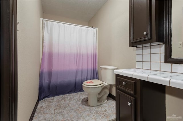 bathroom with vanity, toilet, and backsplash