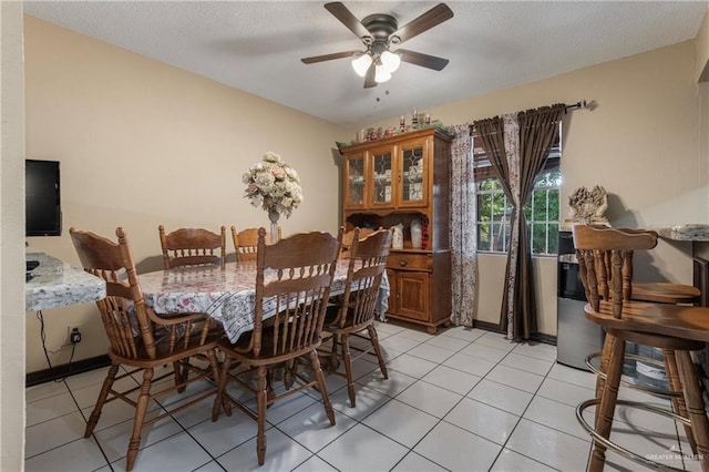 dining space featuring a textured ceiling, ceiling fan, and light tile patterned flooring