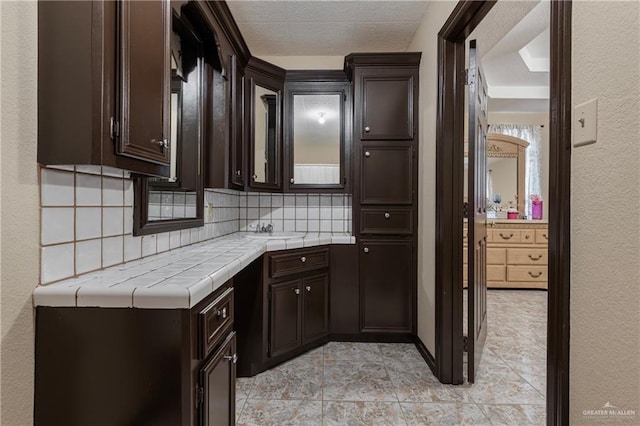 kitchen featuring decorative backsplash, dark brown cabinets, and light tile patterned floors