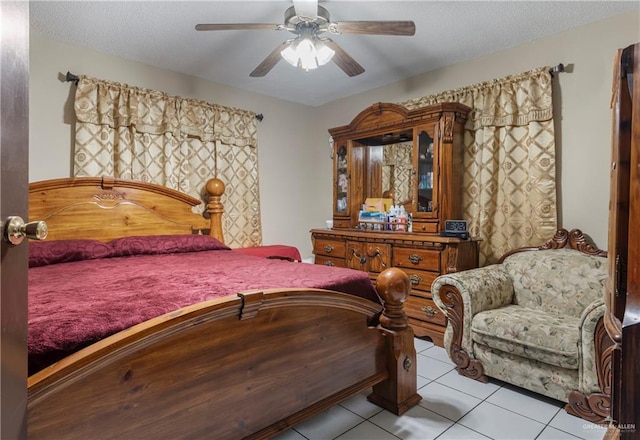 bedroom with ceiling fan, light tile patterned flooring, and a textured ceiling