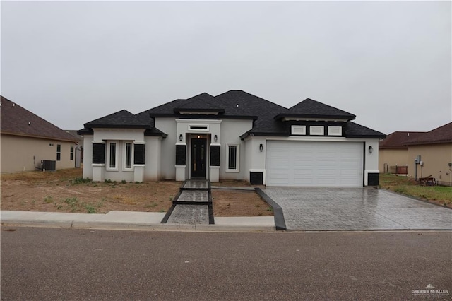 prairie-style house featuring a garage and central air condition unit