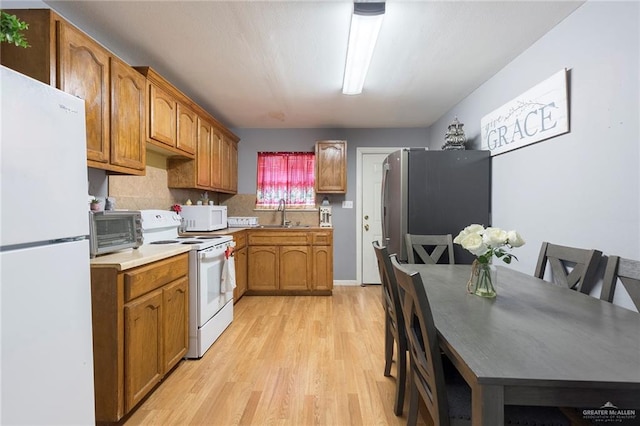 kitchen with sink, light hardwood / wood-style floors, and white appliances