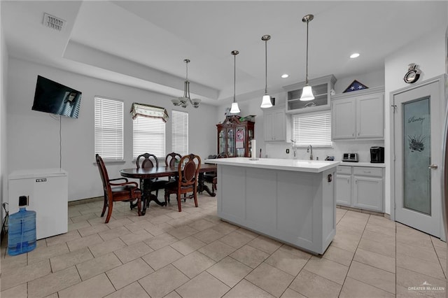 kitchen featuring white cabinets, pendant lighting, a center island, and a tray ceiling