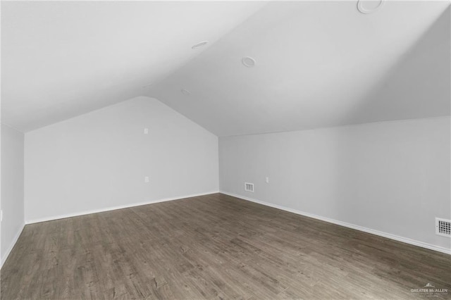 additional living space with dark hardwood / wood-style flooring and vaulted ceiling