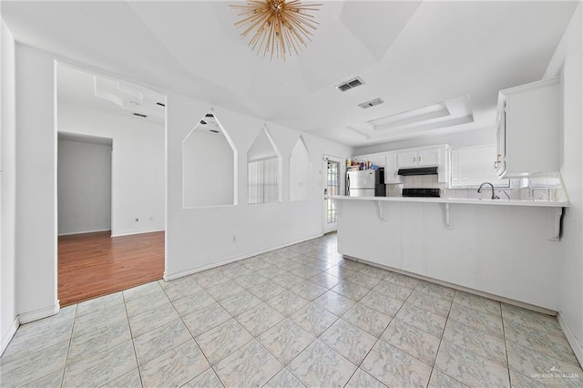 4217 W Ithaca Ave, Mcallen, TX 78501 - kitchen with freestanding refrigerator, under cabinet range hood, a raised ceiling, a peninsula, and light countertops
