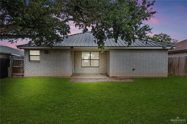 4217 W Ithaca Ave, Mcallen, TX 78501 - back of house at dusk featuring a patio area, brick siding, and metal roof