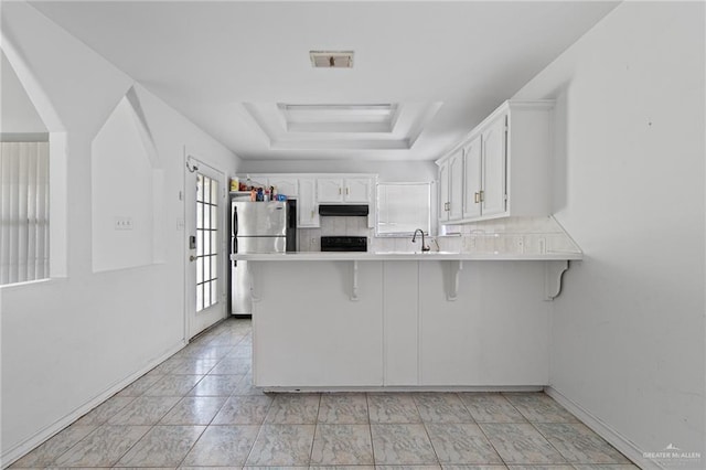4217 W Ithaca Ave, Mcallen, TX 78501 - kitchen featuring a peninsula, freestanding refrigerator, stove, white cabinets, and a sink