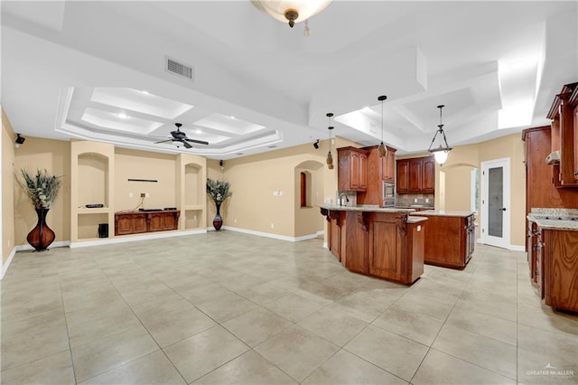 kitchen with pendant lighting, a raised ceiling, and ceiling fan