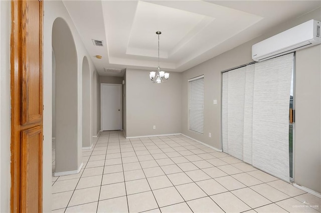 unfurnished dining area with a wall mounted air conditioner, a tray ceiling, a notable chandelier, and light tile patterned flooring