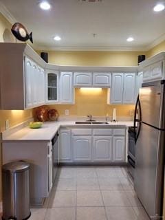 kitchen with stainless steel refrigerator, sink, light tile patterned flooring, and ornamental molding