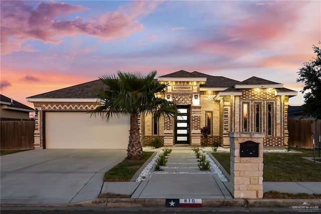 prairie-style home with brick siding, fence, concrete driveway, roof with shingles, and a garage