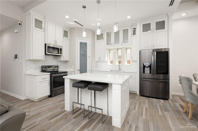 kitchen with light countertops, a breakfast bar area, appliances with stainless steel finishes, and a sink