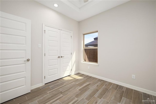 unfurnished bedroom with recessed lighting, baseboards, a closet, and wood finish floors