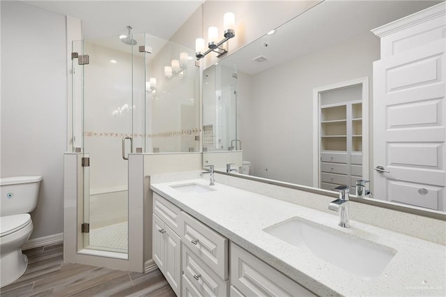 bathroom with a sink, wood finished floors, toilet, and a stall shower