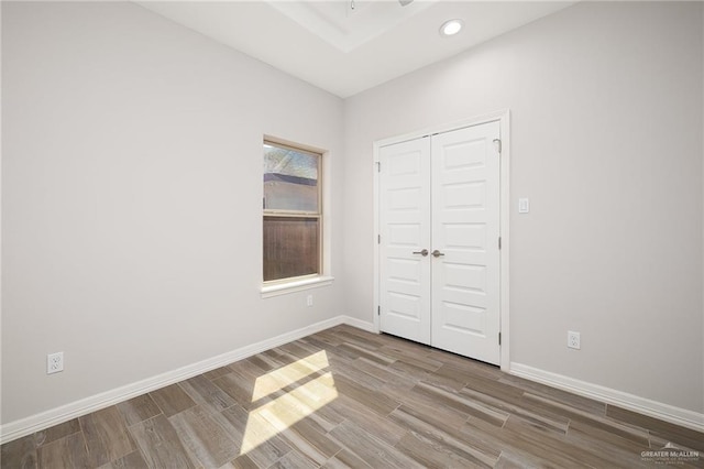 unfurnished bedroom featuring a closet, recessed lighting, baseboards, and wood finished floors