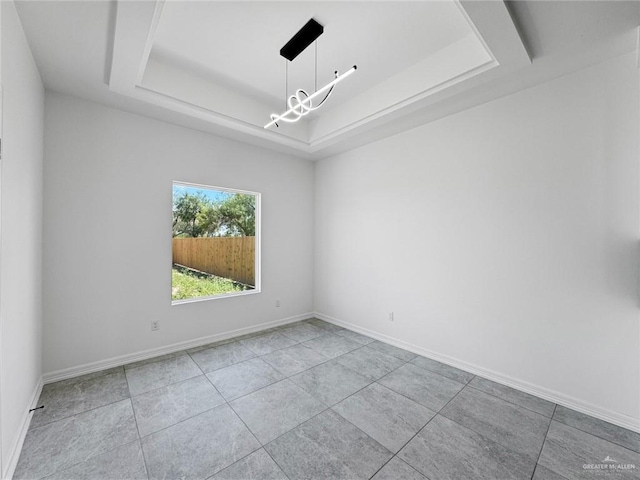 unfurnished room with a tray ceiling and a chandelier