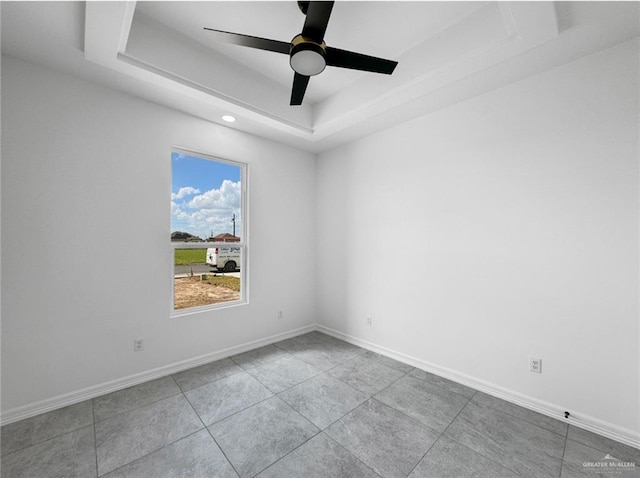 tiled spare room with a raised ceiling and ceiling fan